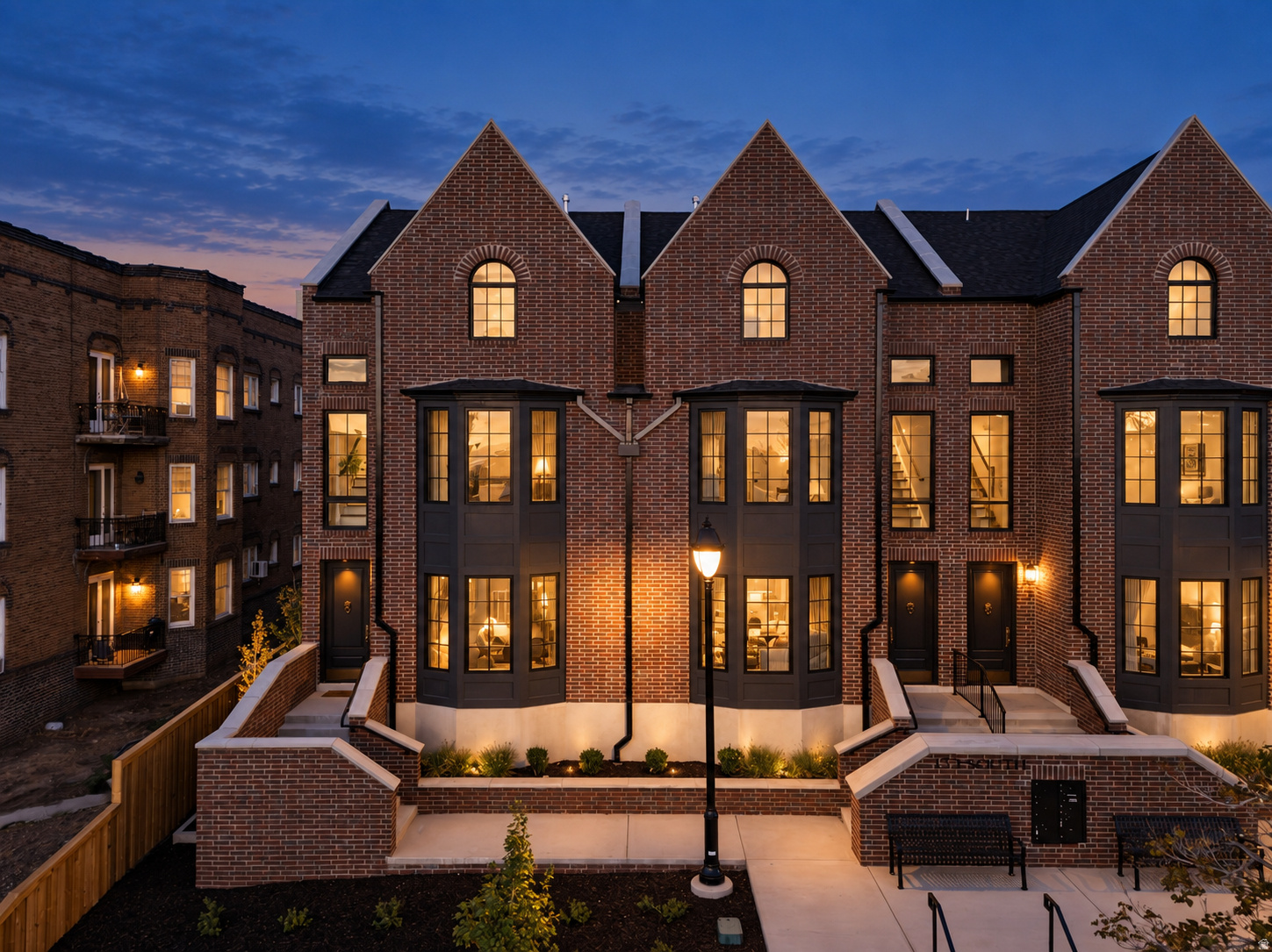 Gabled brick townhomes glowing at blue hour