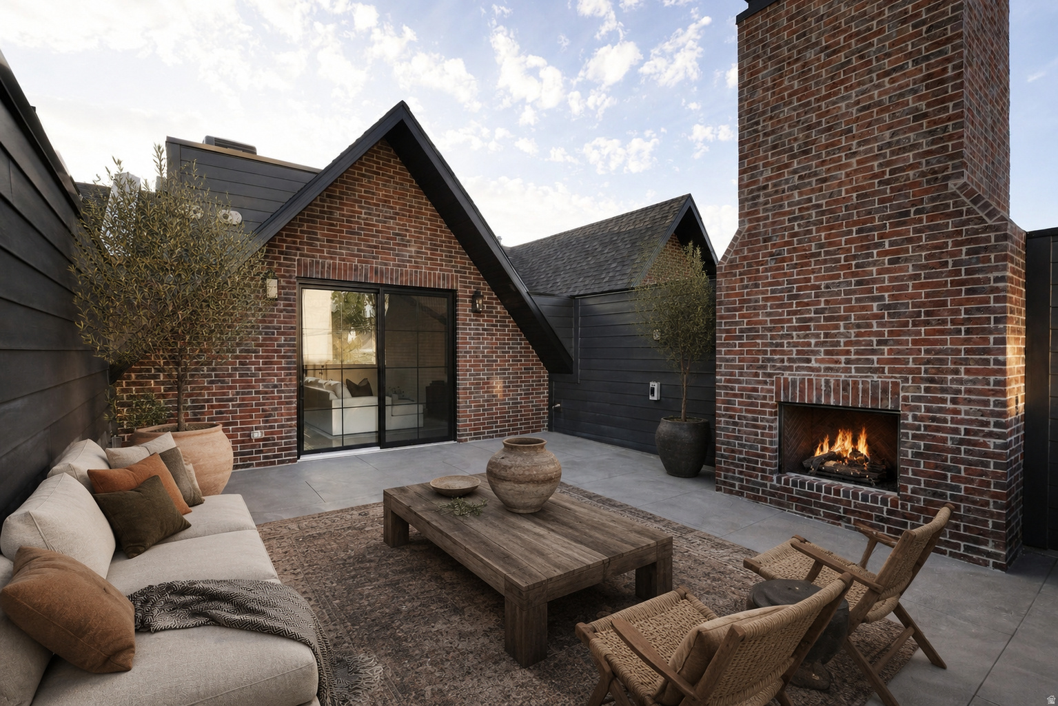 Exterior brick construction with contrasting dark siding, a prominent outdoor fireplace, and a large sliding glass door